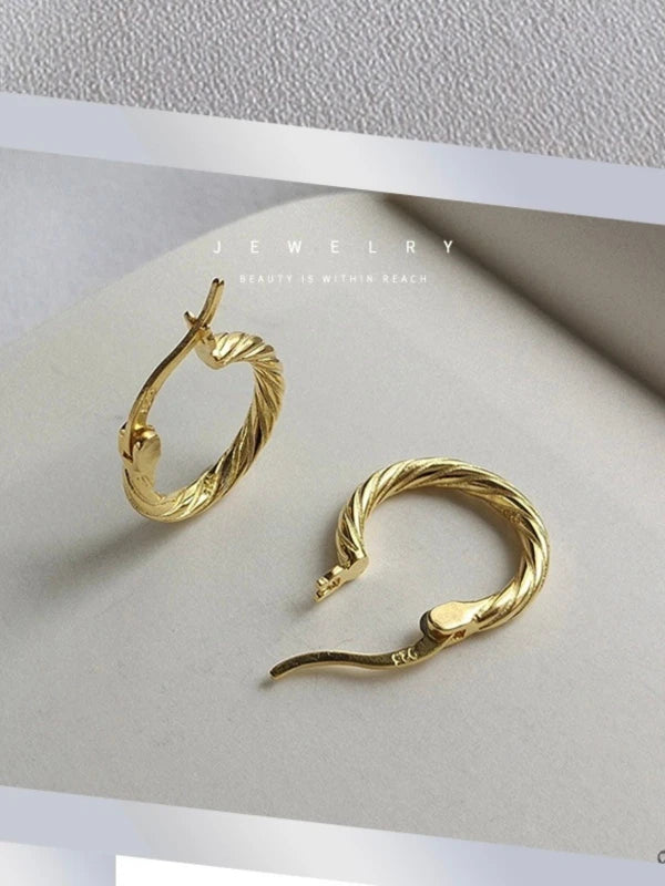 Gold hoop earrings on a white surface.