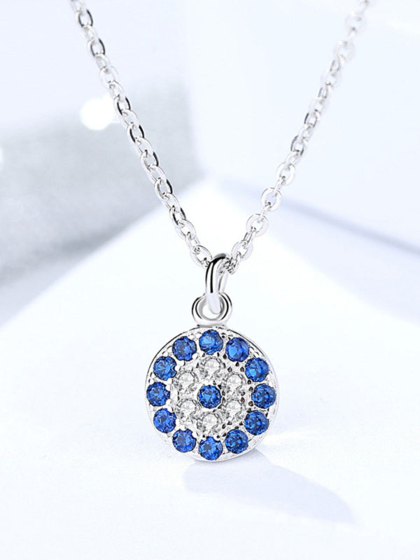 Silver necklace with a round pendant featuring blue stones on a light background