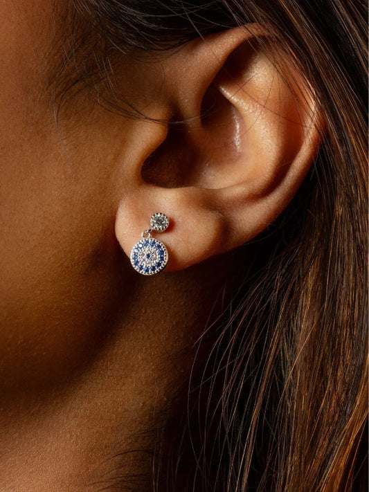 Close-up of an ear wearing a diamond earring with a blurred background