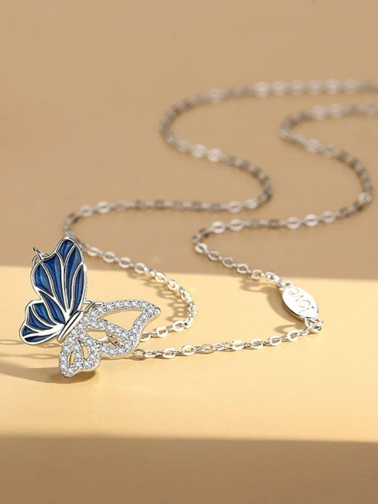 Butterfly-shaped pendant on a chain against a beige background
