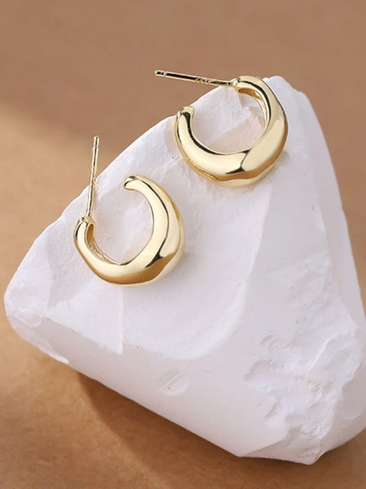 Gold hoop earrings on a white stone with a brown background