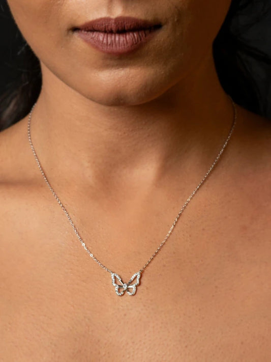 Butterfly necklace on a person's neck with a neutral background