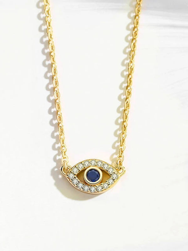 Gold necklace with an eye-shaped pendant featuring a blue gemstone on a white background
