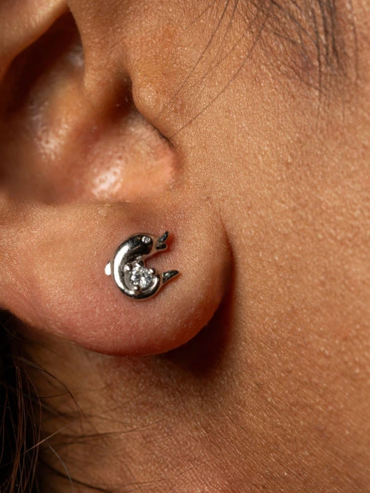 Close-up of an ear with a unique earring featuring a crescent moon and star design.