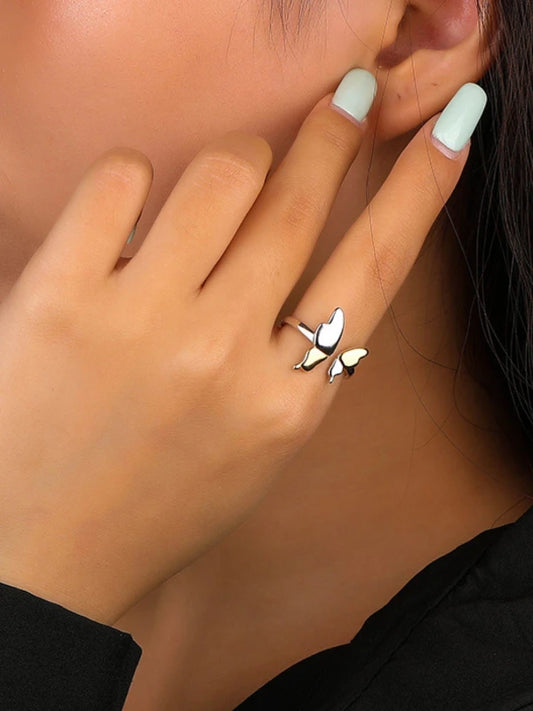 Close-up of a hand wearing a silver ring with a butterfly design.