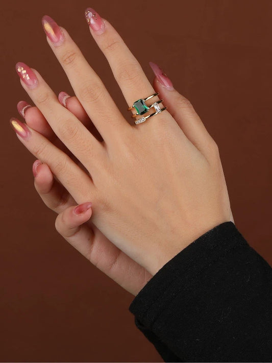 Hand wearing a ring with a green gemstone on a brown background