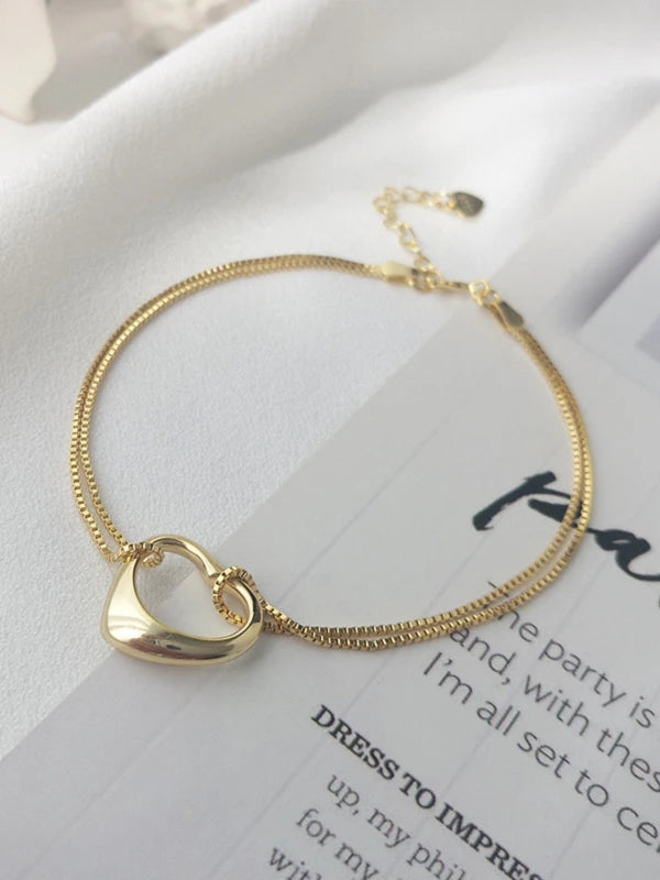 Gold heart-shaped bracelet on a white surface with text