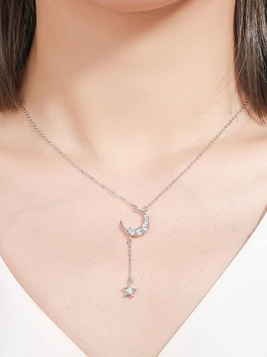 Necklace with a crescent moon and star pendant on a woman wearing a white top.