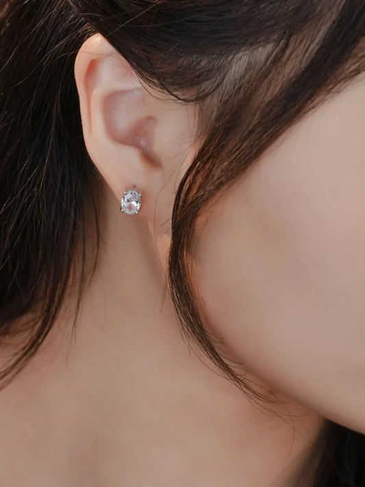 Close-up of an ear wearing a diamond earring with a blurred background
