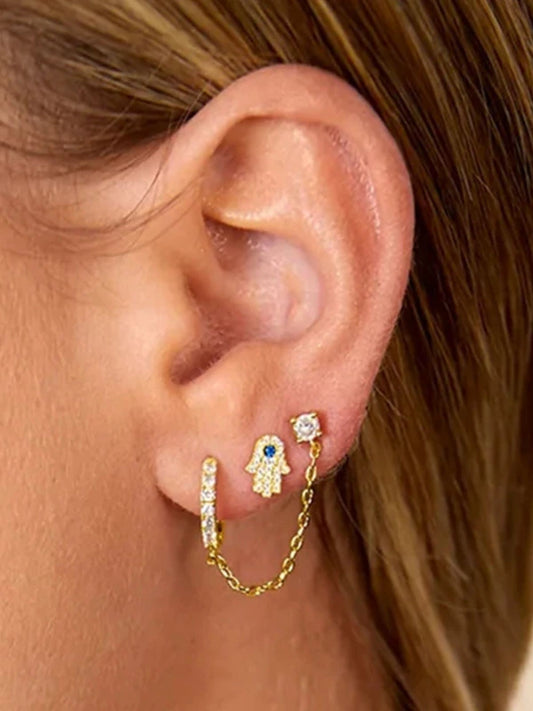 Close-up of an ear wearing gold hoop earrings with a small blue gemstone.