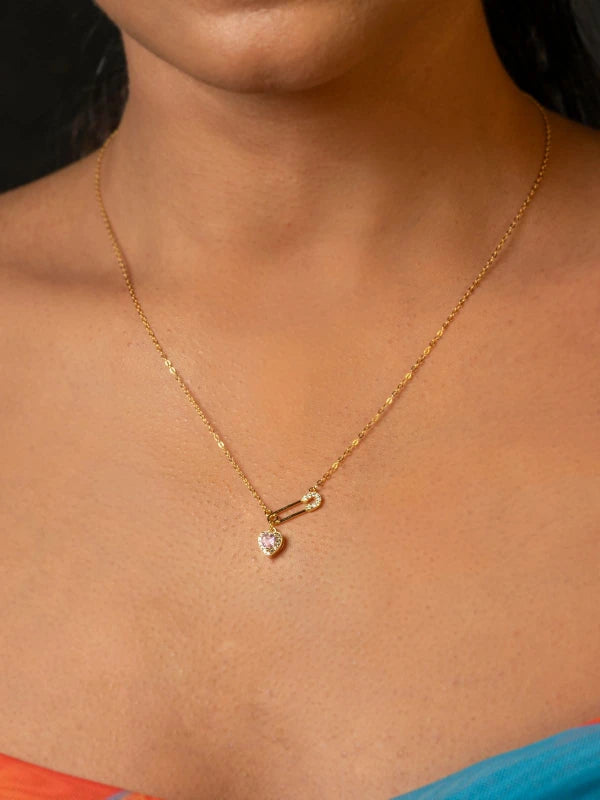 Gold necklace with a heart-shaped pendant on a person's neck