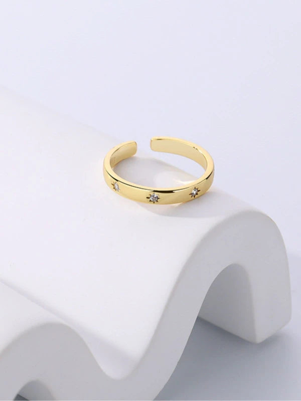 Gold ring with star designs on a white background