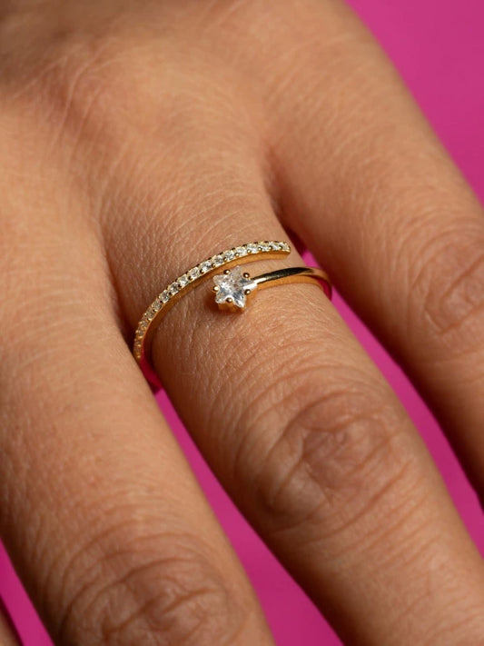 Close-up of a hand wearing a diamond ring on a pink background