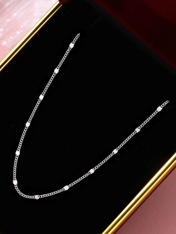 Silver chain necklace on a black background