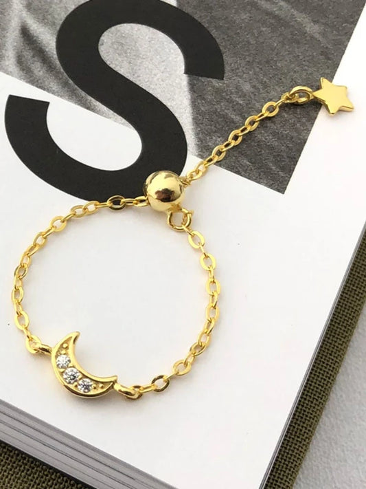 Gold bracelet with moon and star designs on a magazine background