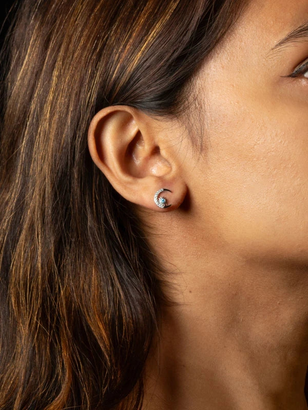 Close-up of an ear wearing a turquoise stud earring with a blurred background
