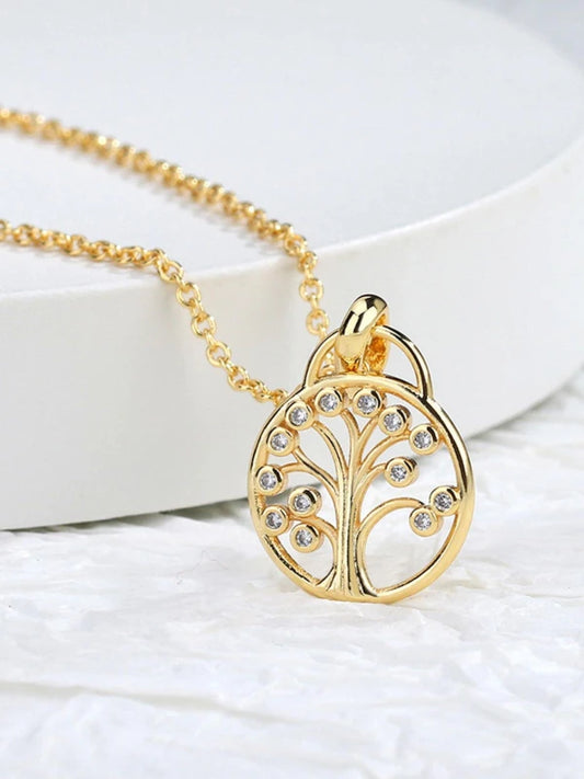 Gold necklace with a tree-shaped pendant on a white surface