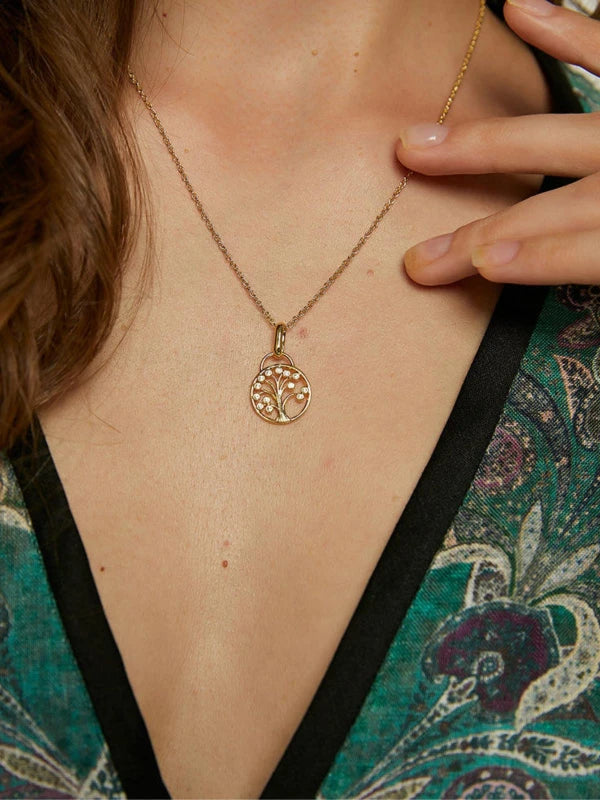 Gold necklace with a tree of life pendant worn by a woman