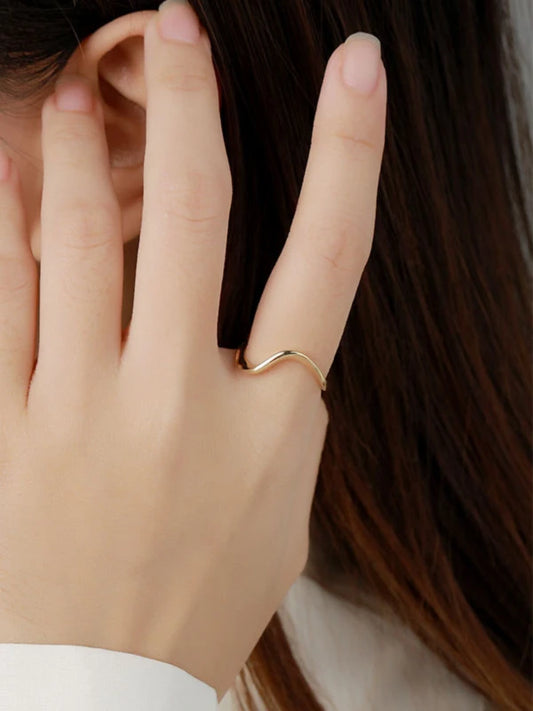 Hand wearing a gold ring with hair in the background