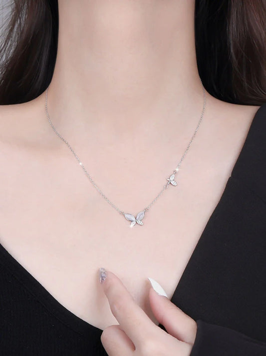 Necklace with butterfly pendants worn by a woman against a neutral background