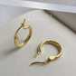 Gold hoop earrings on a white surface.