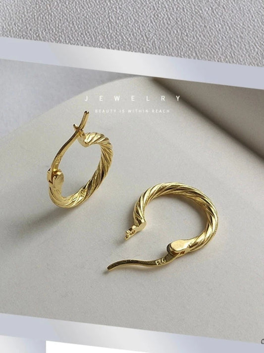 Gold hoop earrings on a white surface.