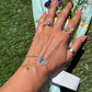 Hand wearing butterfly-themed jewelry with a scenic background