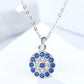 Silver necklace with a round pendant featuring blue stones on a light background