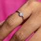 Close-up of a hand wearing a ring with a pink background