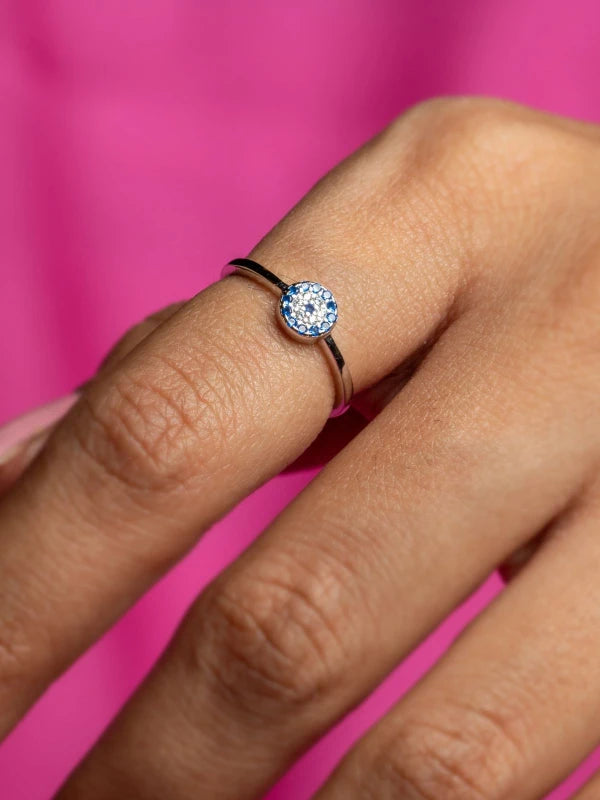 Close-up of a hand wearing a ring with a pink background