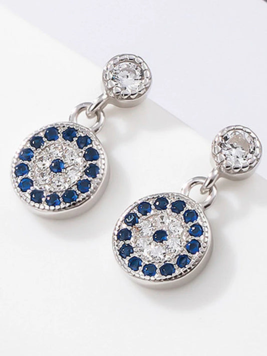 Pair of silver earrings with blue gemstones and clear stones on a white background