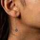 Close-up of an earring with a blue gemstone on a woman's ear.