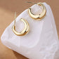 Gold hoop earrings on a white stone with a brown background