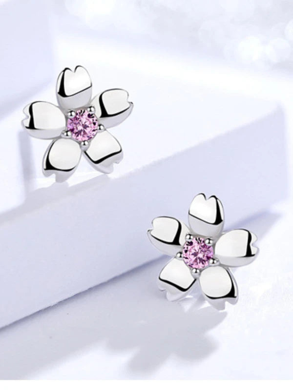 Silver flower-shaped earrings with pink gemstones on a light background