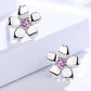 Silver flower-shaped earrings with pink gemstones on a light background