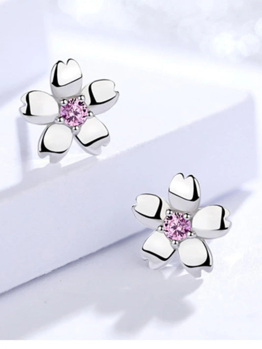 Silver flower-shaped earrings with pink gemstones on a light background