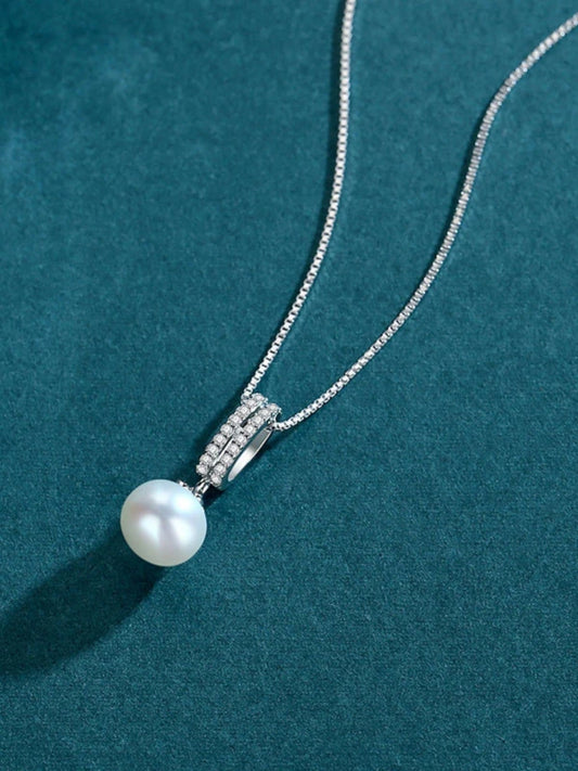Pearl necklace with silver clasp on a teal background