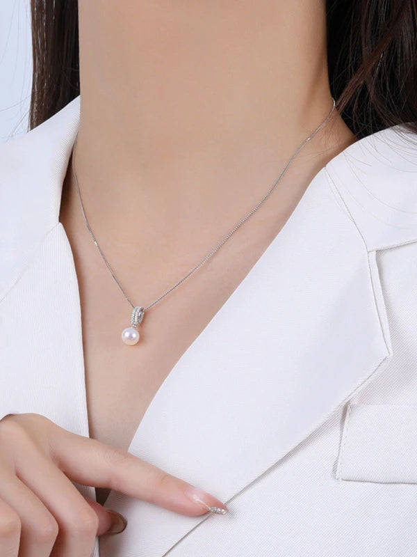Pearl necklace being worn by a person in a white outfit