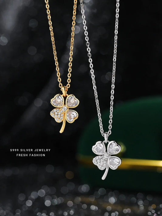 Gold and silver four-leaf clover pendants on dark background