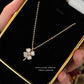 Four-leaf clover silver necklace held by a hand on a black card with gold border