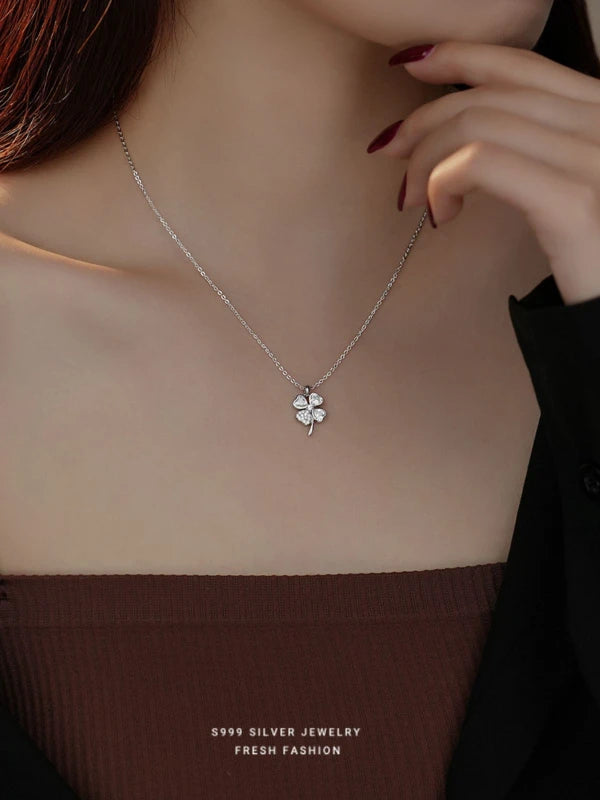 Silver four-leaf clover necklace worn by a woman.