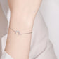 Silver bracelet with a rainbow charm on a wrist against a light background