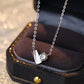 Silver necklace with a heart-shaped pendant on a dark jewelry box