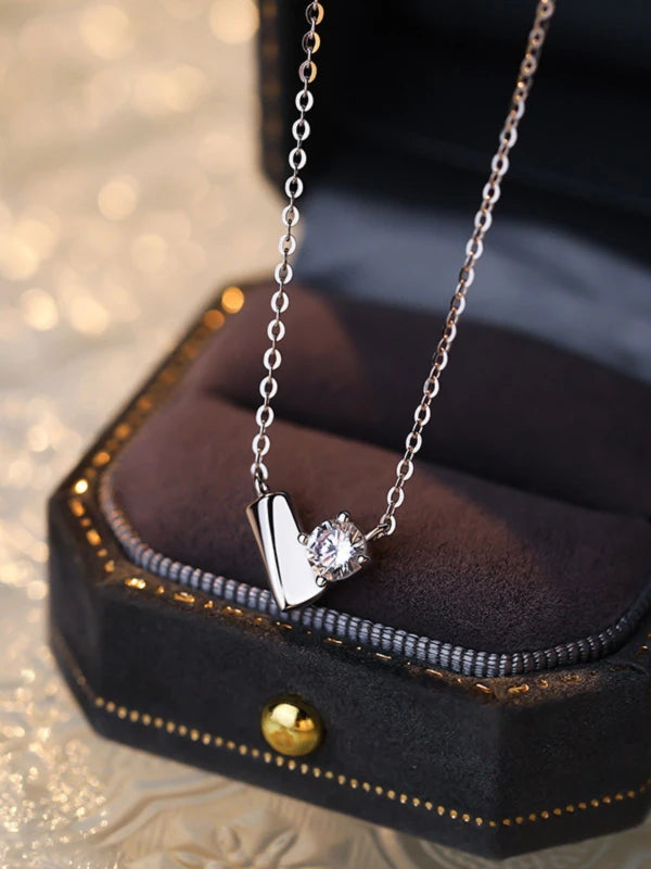 Silver necklace with a heart-shaped pendant on a dark jewelry box
