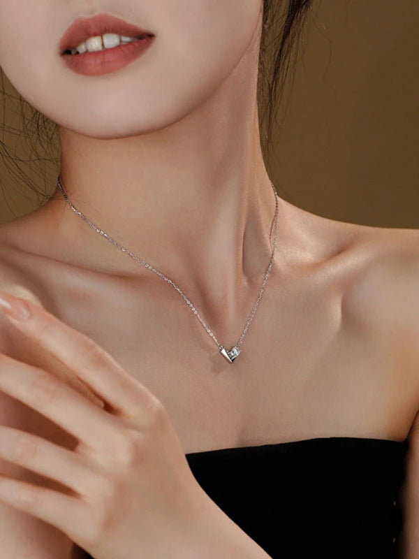 Necklace with a heart pendant worn by a woman against a neutral background