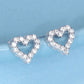 Heart-shaped earrings with clear gemstones on a light blue background