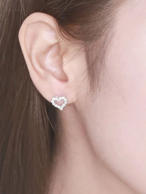 Heart-shaped earrings worn by a woman with brown hair.