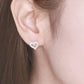 Heart-shaped earrings worn by a woman with brown hair.