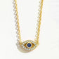 Gold necklace with an eye-shaped pendant featuring a blue gemstone on a white background