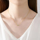 Gold necklace with a small pendant worn by a woman in a white top